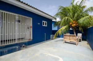 a blue building with a bench and a palm tree at Blue Apartments in Willemstad