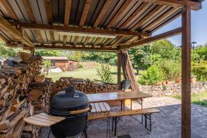 pérgola de madera con mesa y parrilla en Casa di Nonna Adriana en Pieve Fosciana