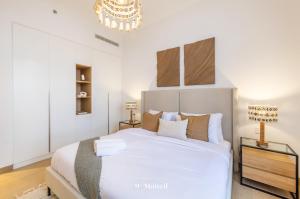 Un dormitorio con una gran cama blanca y una lámpara de araña. en Manzil - 1BR Home in Port de la Mer w Lake Access, en Dubái 12 fotos más
