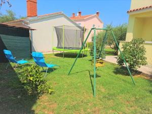 two chairs and a swing set in a yard at Apartments Prodan in Fažana