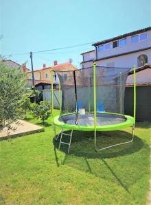 a green trampoline in the grass in a yard at Apartments Prodan in Fažana