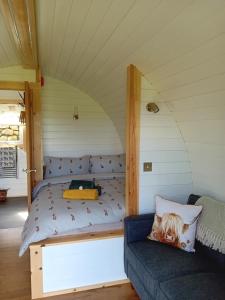 a small bed in a room with a couch at Coombs glamping pods in Danby