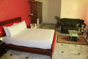 a bedroom with a large bed and a couch at The Ballagio Inn in Islamabad