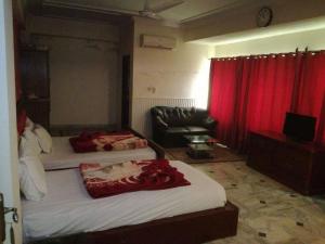 two beds in a room with red curtains and a couch at The Ballagio Inn in Islamabad