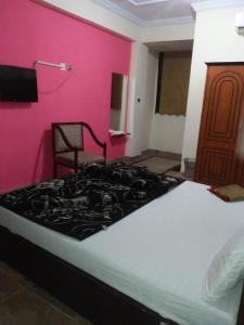 a bed in a room with a pink wall at The Ballagio Inn in Islamabad