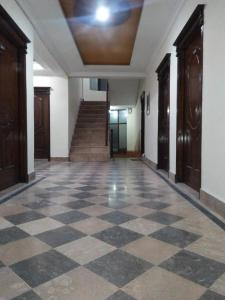 an empty hallway with a checkered floor and stairs at The Ballagio Inn in Islamabad