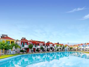 una gran piscina en una ciudad con casas coloridas en Bungalows Vistaflor en Maspalomas