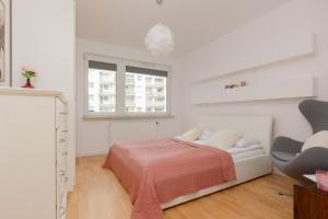 a white bedroom with a bed and a chair at Fort Bema Apartment with Parking by Renters in Warsaw