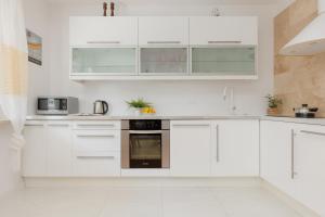 a white kitchen with white cabinets and appliances at Fort Bema Apartment with Parking by Renters in Warsaw
