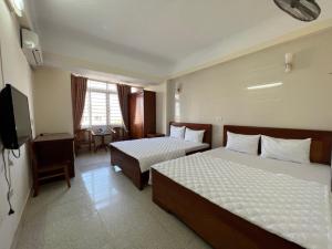 クアローにあるChâu Giang Hotel Cửa Lòのベッド2台とテレビが備わるホテルルームです。