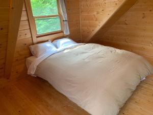 a bed in a log cabin with a window at Place yatsugatake Oigamori cottage - Vacation STAY 93259v in Hokuto