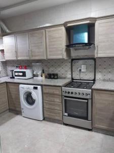 a kitchen with a stove and a washing machine at Adam's Apartment in Amman