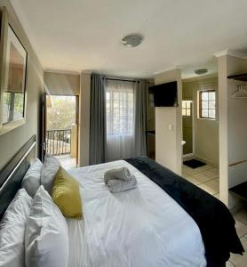ein Schlafzimmer mit einem großen weißen Bett mit gelben Kissen in der Unterkunft The Eden Boulders Hotel and Resort Midrand in Midrand