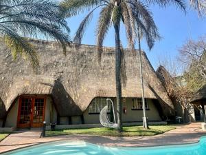 a house with a thatched roof with a swimming pool at The Eden Boulders Hotel and Resort Midrand in Midrand