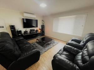 sala de estar con sofá de cuero y TV de pantalla plana en Shore Beats Workin, en Esperance