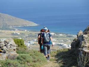 a group of people walking on a hill overlooking the ocean at Tinos youth apartment in Tinos Town