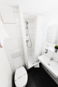 a white bathroom with a toilet and a sink at City Hotel Fellbach 24H CHECK-IN in Fellbach