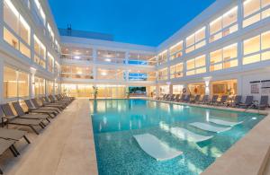 RH Silene Hotel & Spa 4 Sup في كاستيون دي لا بلانا: مسبح كبير في مبنى فيه كراسي