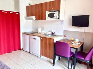 a small kitchen with a table and purple chairs at Adonis Valberg in Valberg