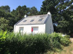a white house with a red window and trees at Appartement dans maison de campagne au calme in La Trinité-sur-Mer