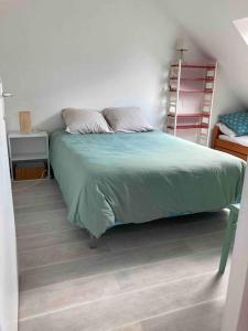 a bedroom with a bed with a green comforter at Appartement dans maison de campagne au calme in La Trinité-sur-Mer