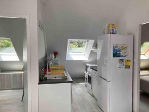 a white kitchen with a refrigerator and a sink at Appartement dans maison de campagne au calme in La Trinité-sur-Mer +9 photos