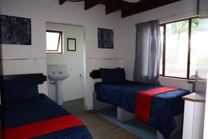- une chambre avec 2 lits, un lavabo et une fenêtre dans l'établissement Whistling Woods, à Empangeni