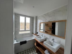 a bathroom with two sinks and a tub and a mirror at Coeur de ville , 70m2 , 2 chambres in Saint-Brieuc