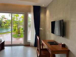 a dining room with a table and a television on the wall at Sokchea Kampot Hotel in Kampot