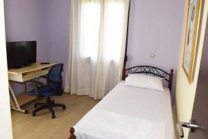 Schlafzimmer mit einem Bett und einem Schreibtisch mit einem Computer in der Unterkunft Villa Spiros in Ioannina