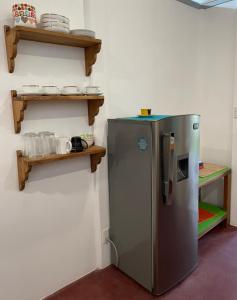 a stainless steel refrigerator in a kitchen with wooden shelves at Casita Coco in Puerto Limón