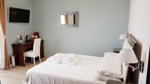 a bedroom with a white bed with a desk and a mirror at Villa Bellavista Alba, B&B in Alba