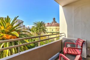 a balcony with two red chairs and palm trees at 437 St Martini Gardens Apartments in Cape Town