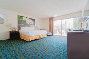 a hotel room with a bed and a balcony at Royal Plaza Inn in Indio