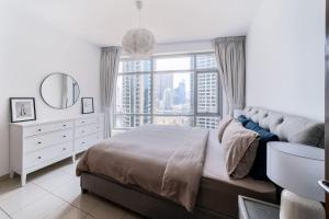 een slaapkamer met een bed en een groot raam bij Heart of the Marina - 1 BR apartment in Dubai