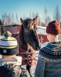 a woman standing next to a horse in the snow at Valkeisen Loma in Ähtäri