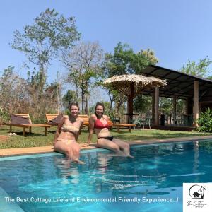 zwei Frauen in Badeanzügen, die im Pool sitzen in der Unterkunft The Cottage Sigiriya in Sigiriya