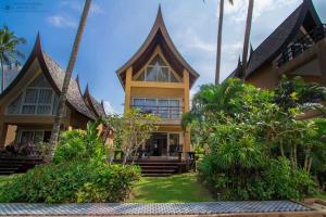 an exterior view of a house with palm trees at Sunrise Beach Villa in Ko Chang