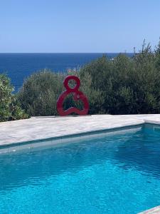 a large swimming pool with a red sculpture next to it at Villa Nafsika stunning view on the Aegean Sea in Áyioi Apóstoloi