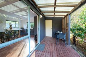 a room with a wooden deck with a table at Seascape Cottage - Mahinepua Bay Clifftop Retreat in Mahinepua