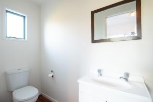 a bathroom with a toilet and a sink and a mirror at Seascape Cottage - Mahinepua Bay Clifftop Retreat in Mahinepua