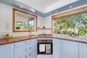 a kitchen with white cabinets and a sink and a window at Seascape Point - Mahinepua Bay Clifftop Retreat in Mahinepua