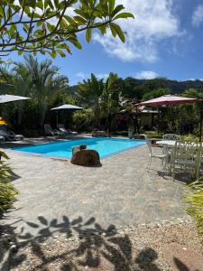 a swimming pool with a table and chairs next to it at La Digue Holiday Villa in La Digue