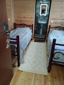 two beds in a room with a sink and a mirror at HOTEL AMIRAN in Tusheti