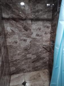 a bathroom with a shower with a stone wall at HOTEL AMIRAN in Tusheti