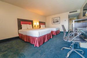 a hotel room with two beds and a desk and chairs at Royal Plaza Inn in Indio