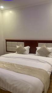 a large white bed with white pillows on it at Fakher Yanbu 3 Furnished Units in Yanbu
