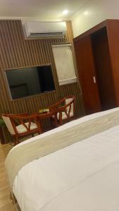 a bedroom with a bed and a television and a table at Fakher Yanbu 3 Furnished Units in Yanbu