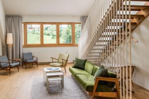 a living room with a green couch and stairs at Landgut am Pößnitzberg in Leutschach