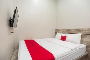 1 dormitorio con cama blanca y manta roja en RedDoorz Plus at Eskole ITERA Lampung, en Lampung